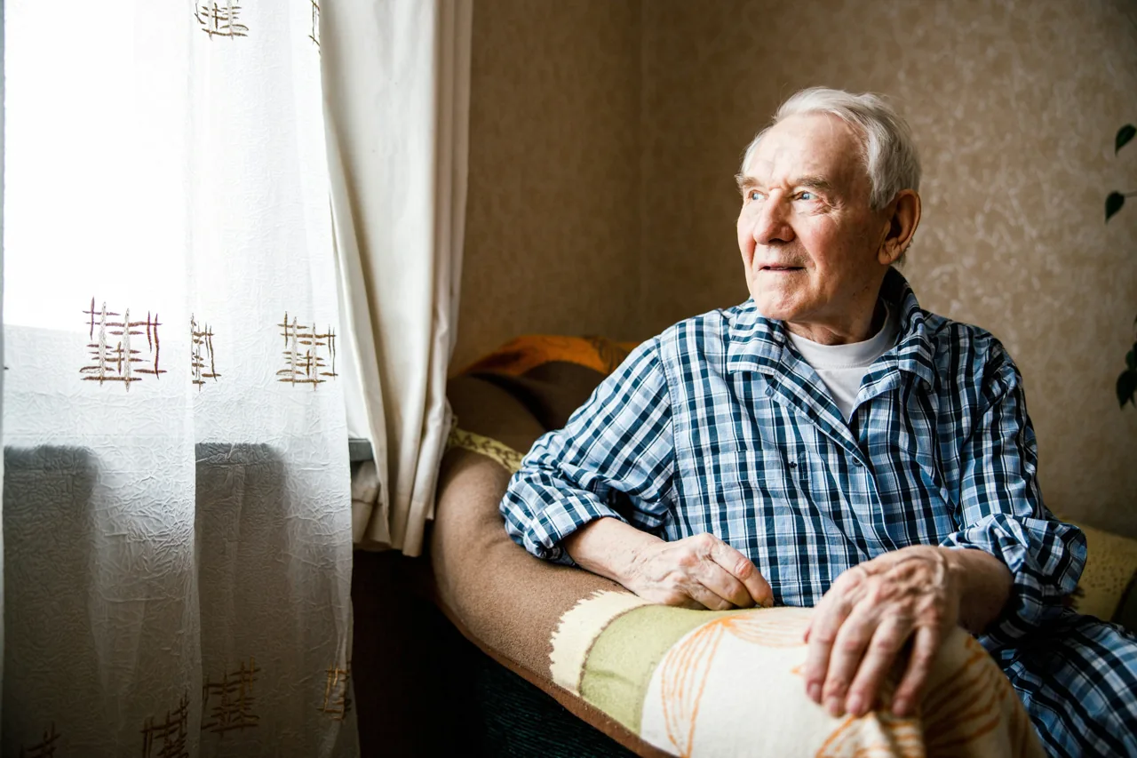 A man sitting comfortably at home beside a window