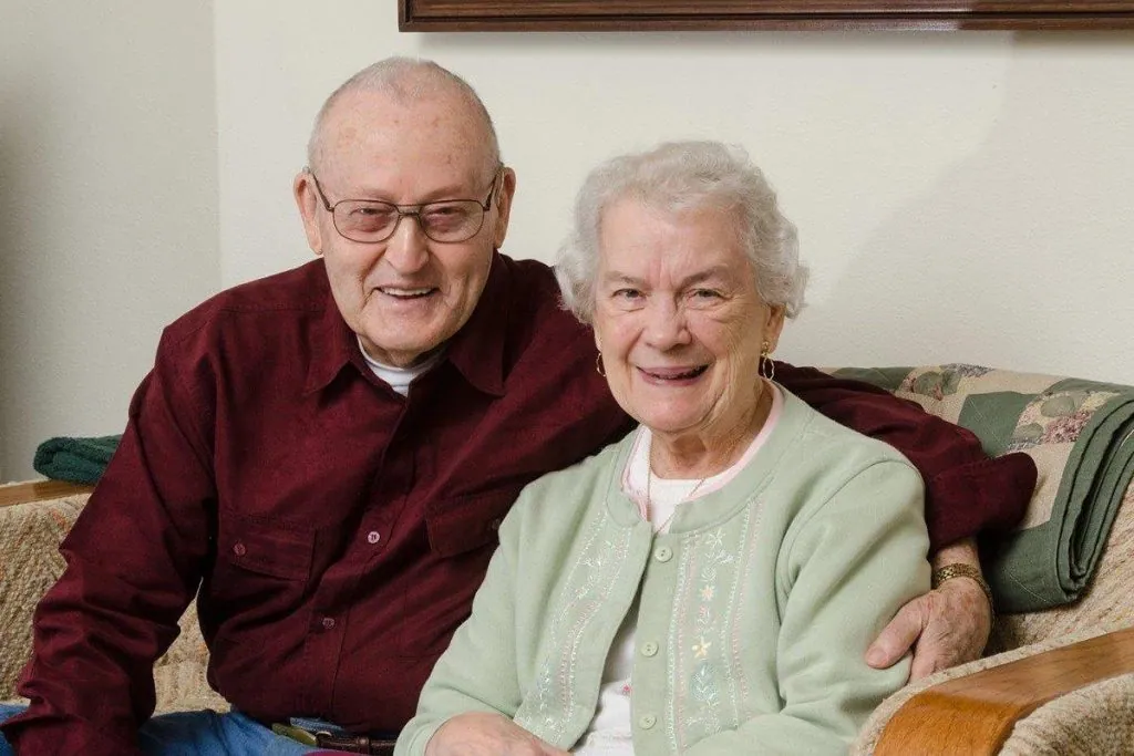 Two actors pictured as an older couple at home