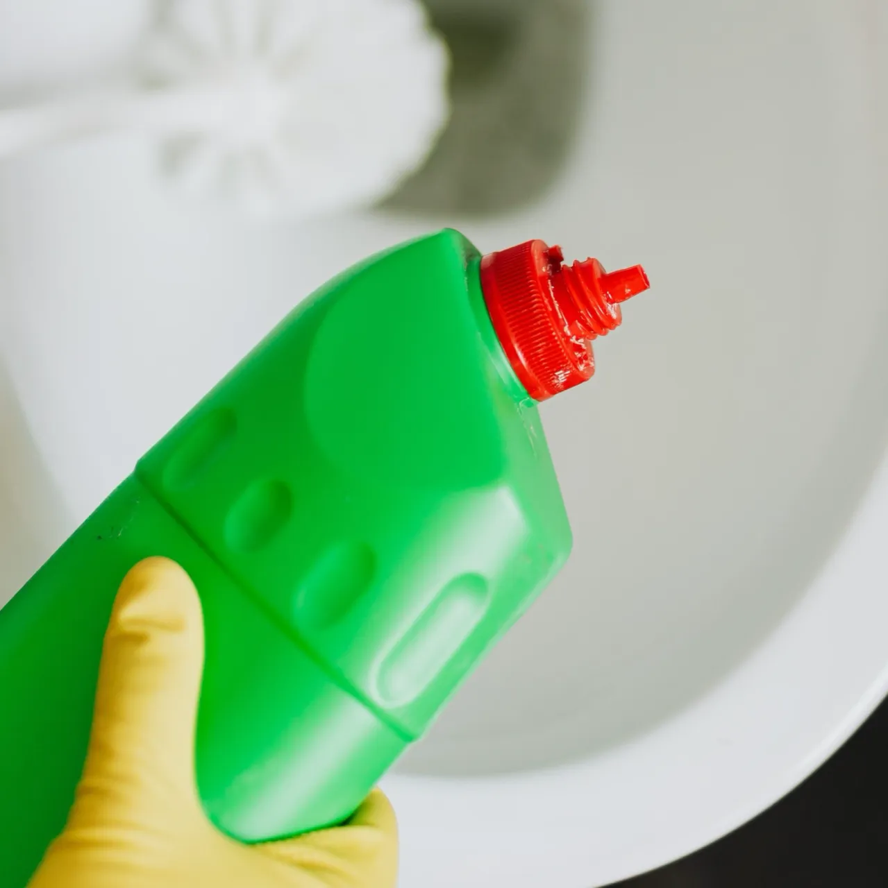 Cleaning a blocked toilet with bleach and rubber gloves