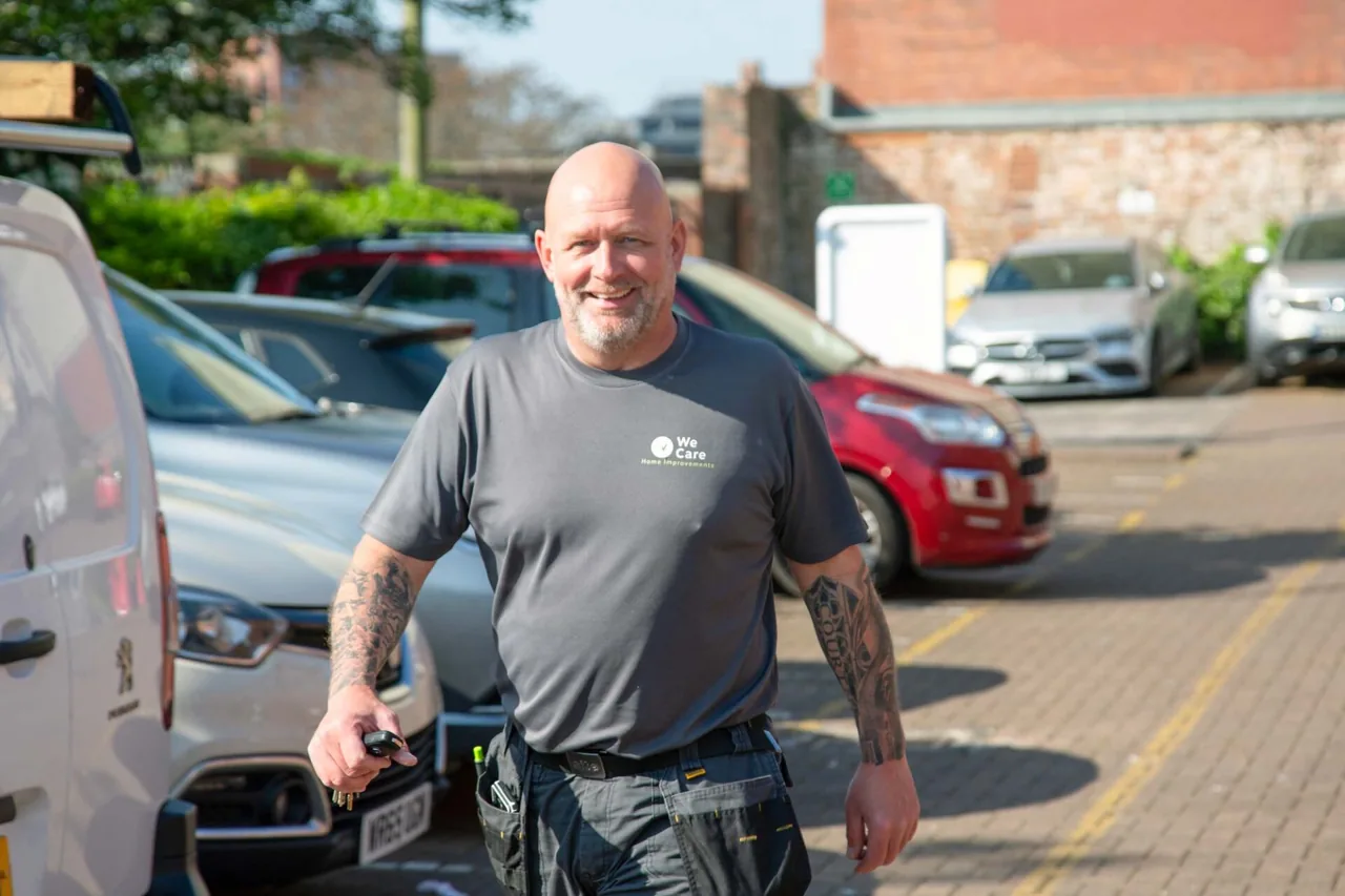 A We Care Home Improvements handyperson beside the team van